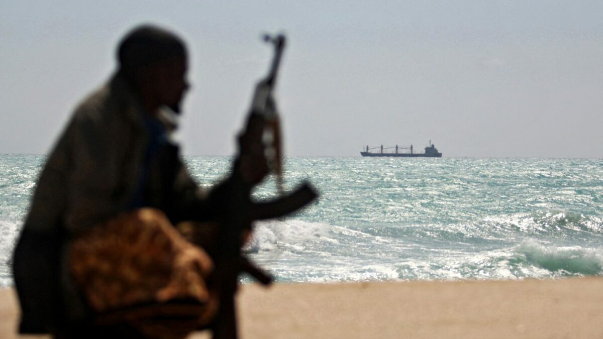 An armed Somali pirate along the coastline while the Greek cargo ship, MV Filitsa, is seen anchored just off the shores of Hobyo town in northeastern Somalia where its being held by pirates.