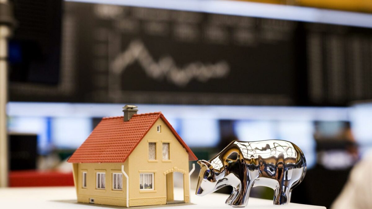 Photo of a house and a symbol of the stock market